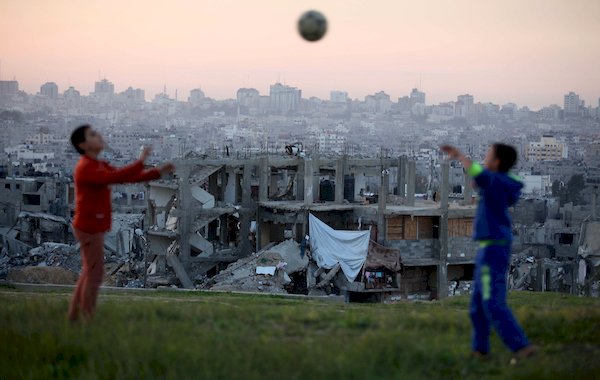 غزة: طفلان فلسطينيان يلعبان بالكرة على أنقاض منزلهم المدمر جراء عدوان 2014