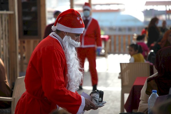 نوادل فلسطينيون يرتدون ازياء بابا نويل في مقهى على شاطئ مدينة غزة