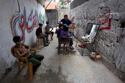 بالصور.. الحلاق الفلسطيني سامح القصاص  يرتدي قناعا وقفازات ويحلق لزبائنه مجانا في ظل كورونا بغزة