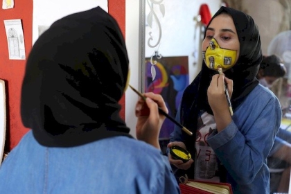 بالصور : رنين الزريعي 18 عام تنفذ أعمال فنية برسم الكمامة على وجوه الأطفال لترغيبهم في ارتدائها في ظل انتشار كورونا في غزة