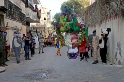 مهرجون يقدمون عروضاً ترفيهية للأطفال المعزولين بمنازلهم، خلال فترة حظر التجول في دير البلح وسط قطاع غزة.