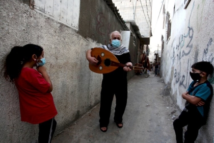 #صور.. توفيق شناعة يعزف على العود لأداء أغاني فلسطينية تقليدية في مخيم رفح في مدينة رفح جنوب قطاع غزة وهو يرتدي الكمامة الطبية