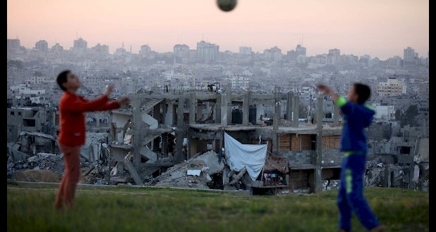 غزة: طفلان فلسطينيان يلعبان بالكرة على أنقاض منزلهم المدمر جراء عدوان 2014