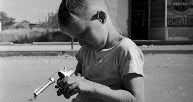 طفل أميركي يلهو بمسدس